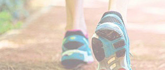 A close up of a person's feet wearing sneakers shows the front foot flat and the back foot mid-stride in an example of onset and recovery from freezing of gait.